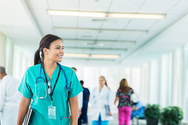 cheerful hispanic nurse walks in hospital corridor - happiness student cheerful lifestyle imagens e fotografias de stock