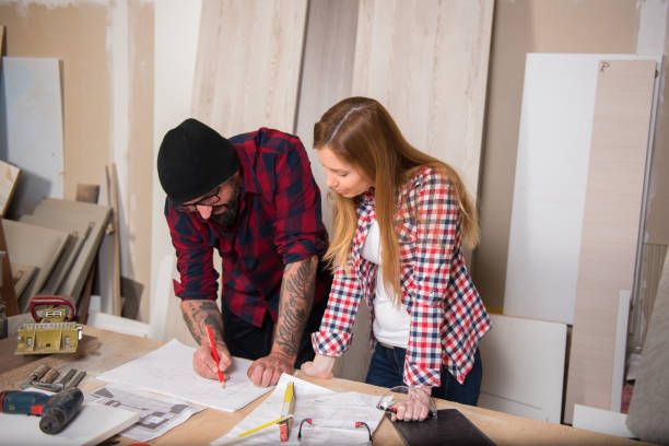 istock Woman and man using power tools in a carpenter workshop 639760050