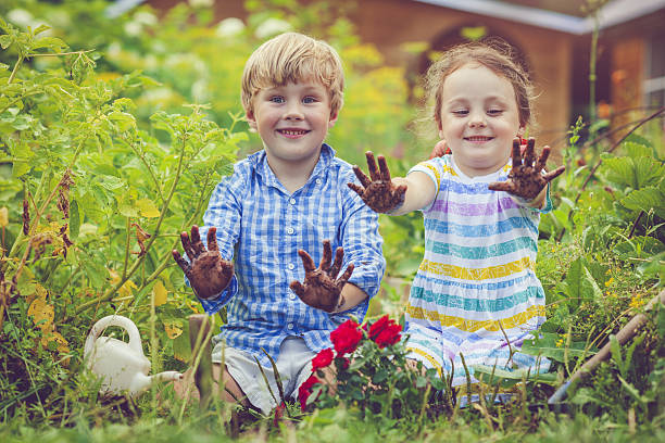 happy little girl and boy in garden - gardening single flower house flower imagens e fotografias de stock