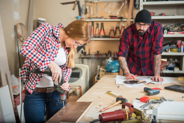 istock Woman and man using power tools in a carpenter workshop 639763264