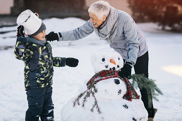 nonna e suo nipote che fanno pupazzo di neve - cold discussion outdoors snow foto e immagini stock