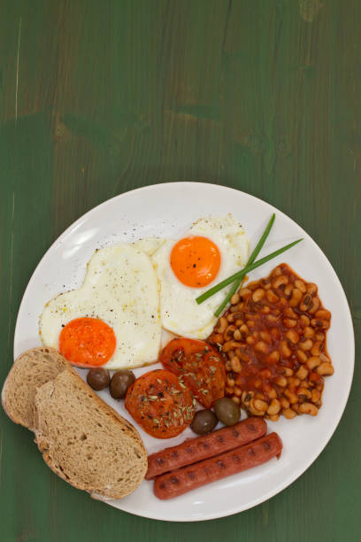 fried eggs with bread, sausages and beans on white plate