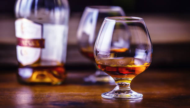 one half full glasses of cognac on a wooden surface. - action alcohol alcoholism bar imagens e fotografias de stock