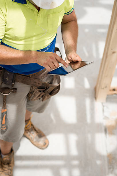 デジタルタブレットでのレビューを計画する - construction worker digital tablet belt building contractor ストックフォトと画像