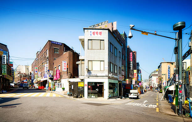 Seoul backstreets panorama on a sunny morning. The small streets are lined with various restaurants and commerces with bright advertising signs.