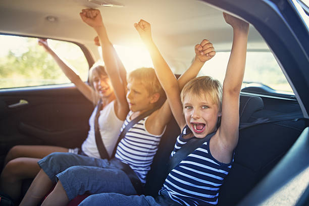 niños divirtiéndose en coche en un viaje por carretera - child laughing blond hair three people fotografías e imágenes de stock