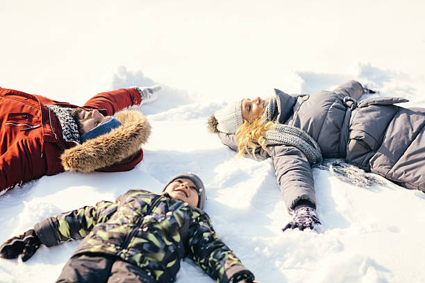 Snow Angels Portrait of family making snow angels. snow angels stock pictures, royalty-free photos & images
