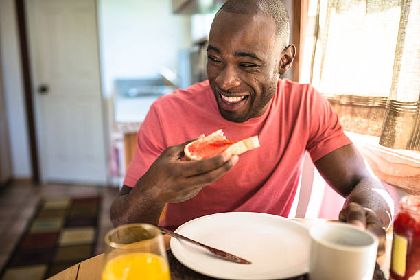 afrikanische mann tun frühstück wie zu hause fühlen. - toast preserves breakfast bread stock-fotos und bilder