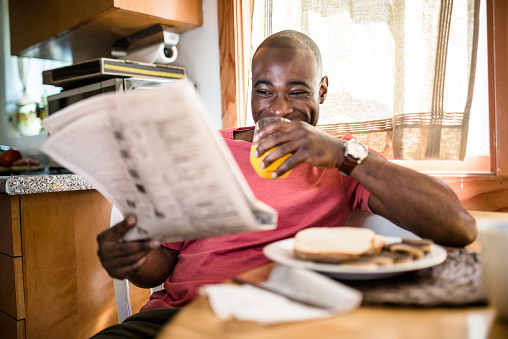 african guy doing breakfast and reading the newspaper