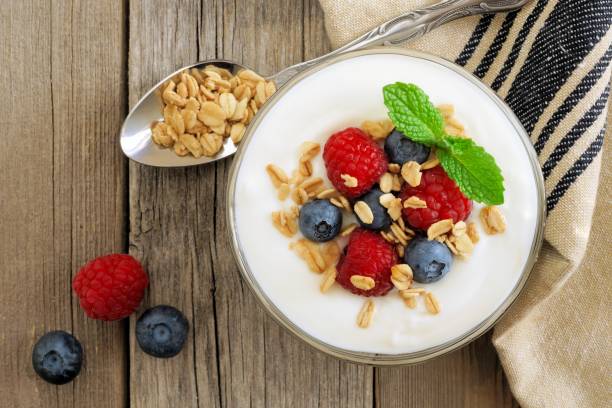 istock Yogurt with raspberries, blueberries, granola, overhead scene on rustic wood 639777086