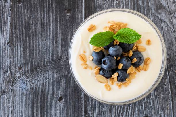 istock Yogurt with blueberries, granola, above view on rustic dark wood 639777118