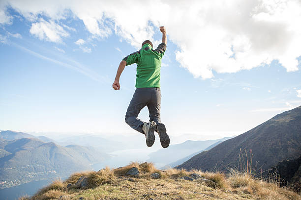 istock Young hiking man on mountain top jumping for success 639778046