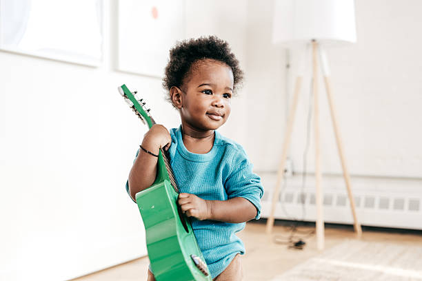 African-American boy with electric guitar on yellow background
