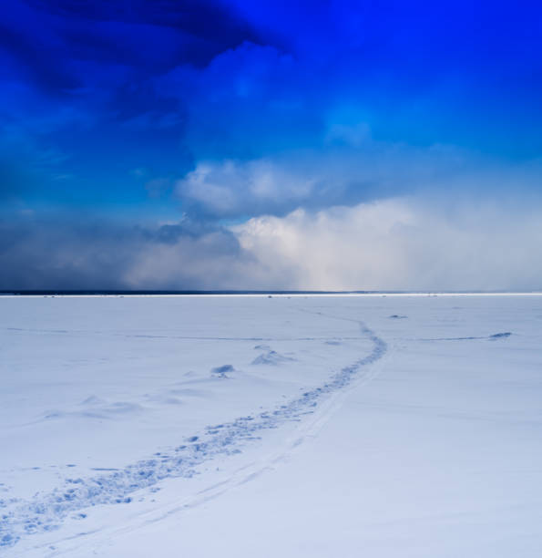 istock Square vivid winter morning on frozen lake footprints path cloud 639780220
