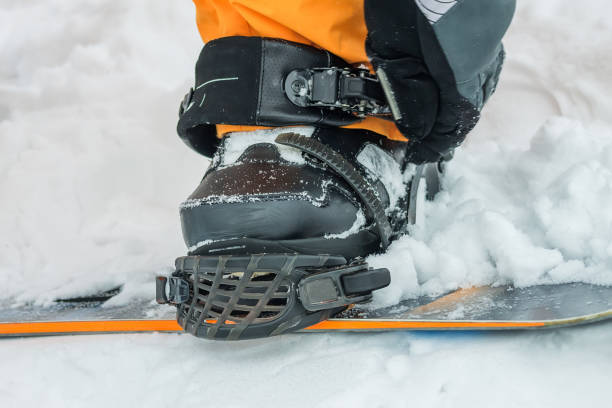 istock The man in black boots buttons fastening snowboard 639783248
