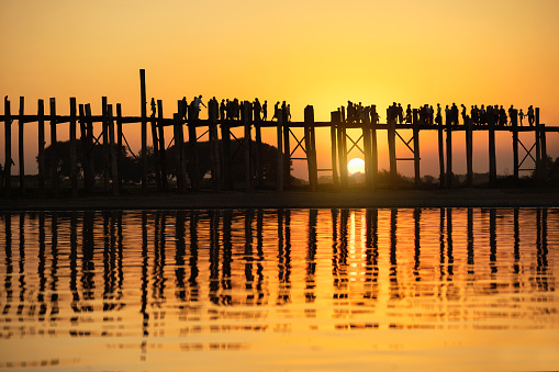 Silhouette of people traveling across the U Bein Bridge in the evening. Mandalay Myanmar