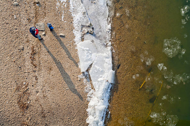 Budapest, Hungary - January 21, 2017: People standing on icy river bank watching the river run at sunrise, aerial view