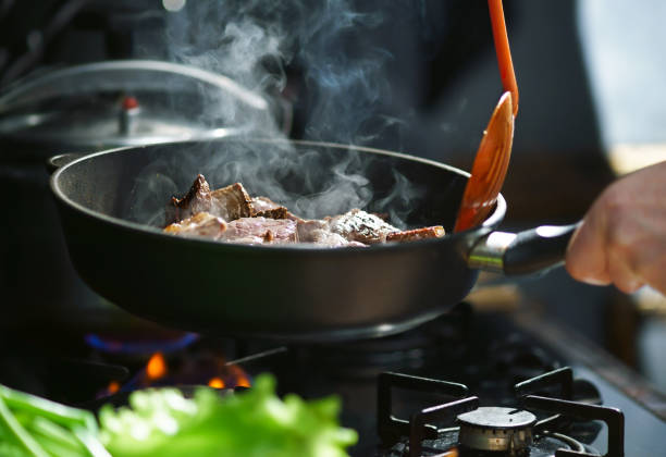 Cooking meat in a frying pan Man cooks meat in a frying pan burner stove top photos stock pictures, royalty-free photos & images