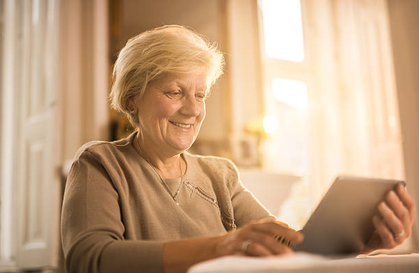 istock Smiling old woman using digital tablet at home. 639794192