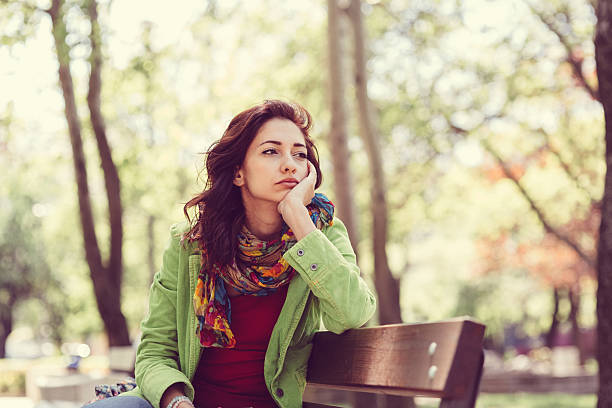 Unhappy girl sitting at bench Thoughtful woman in the park park bench stock pictures, royalty-free photos & images