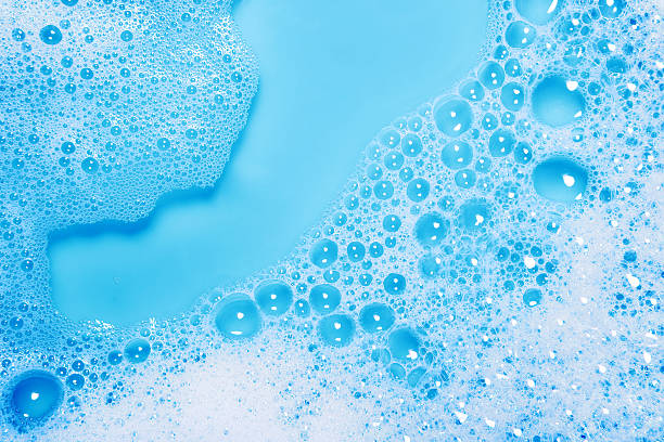 Soap sud close-up (blue) Close-up of soap sud with water on a blue background. soap sud foam bubble laundry stock pictures, royalty-free photos & images