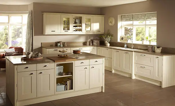 Image of a traditional large kitchen Shaker style interior with kitchen accessories with sun shining through the windows