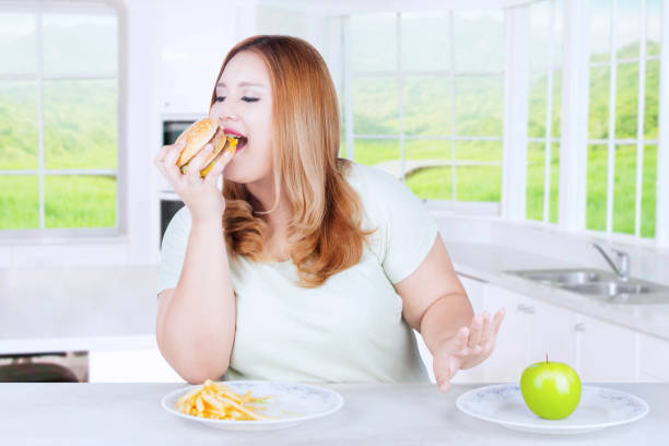 istock Blonde woman eating burger in kitchen 639802976