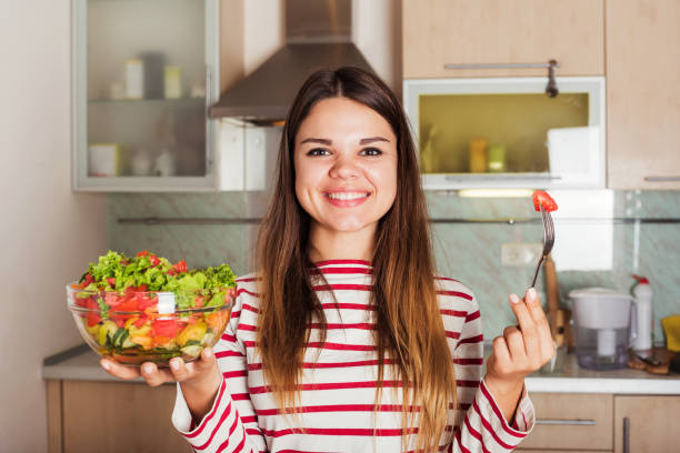 istock young caucasian female eating salad on kitchen 639805680