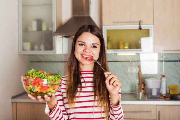 istock young caucasian female eating salad on kitchen 639805940
