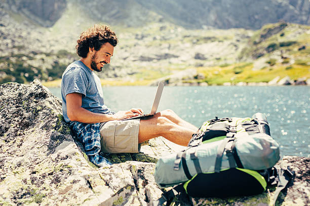 uomo utilizzando un computer portatile in montagna - vacations holiday internet summer foto e immagini stock