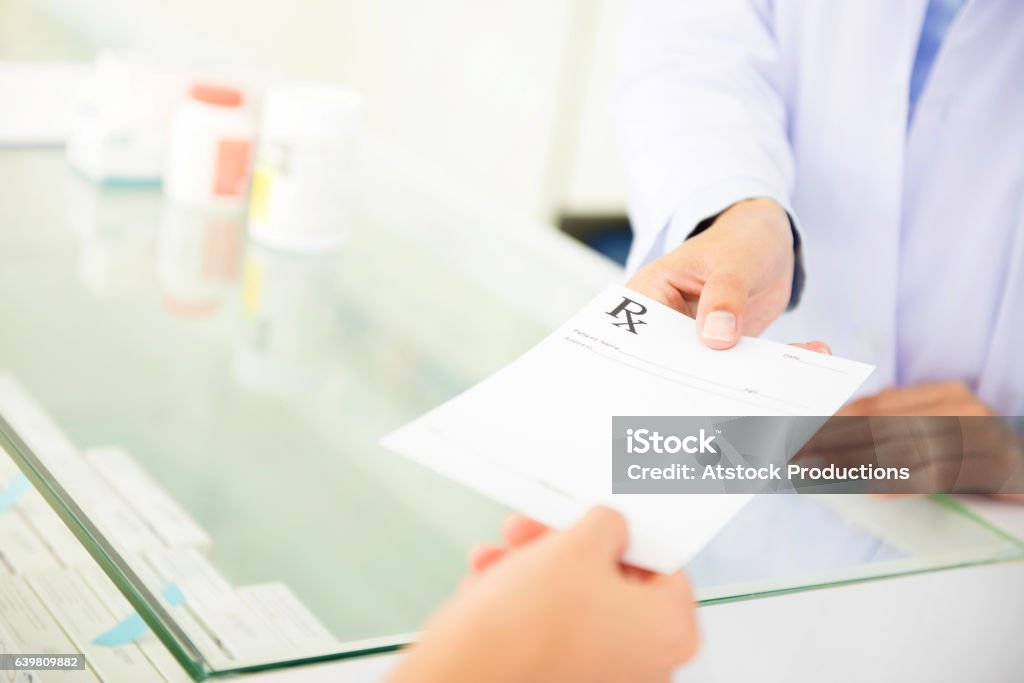 Customer (patient) giving prescription to pharmacist Customer (patient) giving prescription to pharmacist in pharmacy Prescription Stock Photo