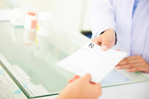 Customer (patient) giving prescription to pharmacist stock photo