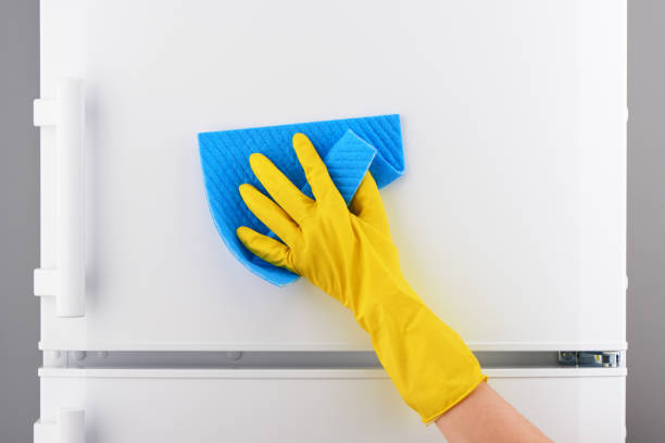 istock Hand in yellow glove cleaning white refrigerator with blue rag 639810012