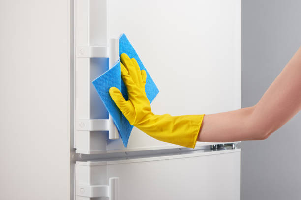 istock Hand in yellow glove cleaning white refrigerator with blue rag 639810796