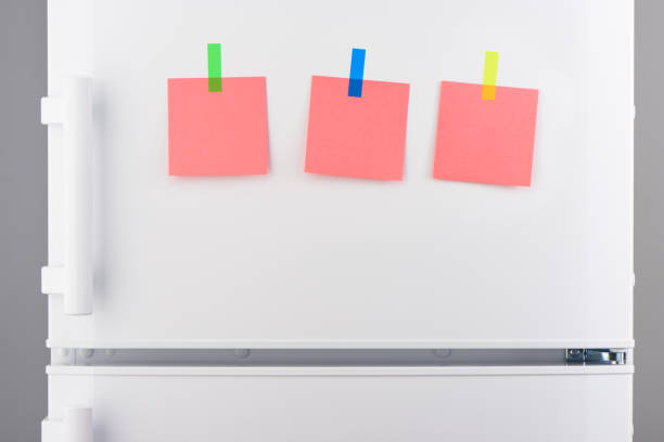 istock Pink paper notes attached with stickers on white refrigerator 639811520