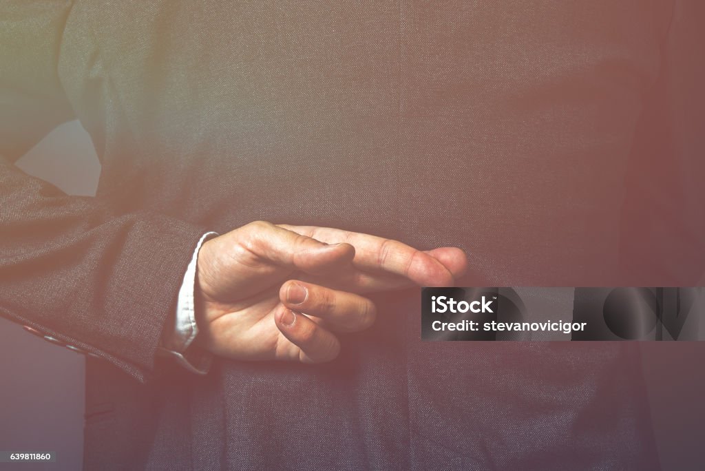Politician telling lies Dishonest politician telling lies, lying government representative holding fingers crossed behind his back Dishonesty Stock Photo