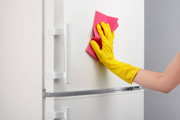 istock Hand in yellow glove cleaning white refrigerator with pink rag 639811930