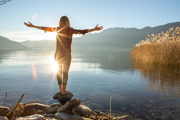 Young woman embracing nature, mountain lake Young cheerful woman by the lake enjoying nature. Arms outstretched for positive emotion.  arms outstretched photos stock pictures, royalty-free photos & images