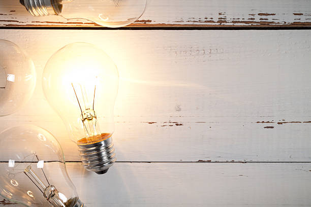 istock Vintage incandescent bulbs on white wooden table 639820716