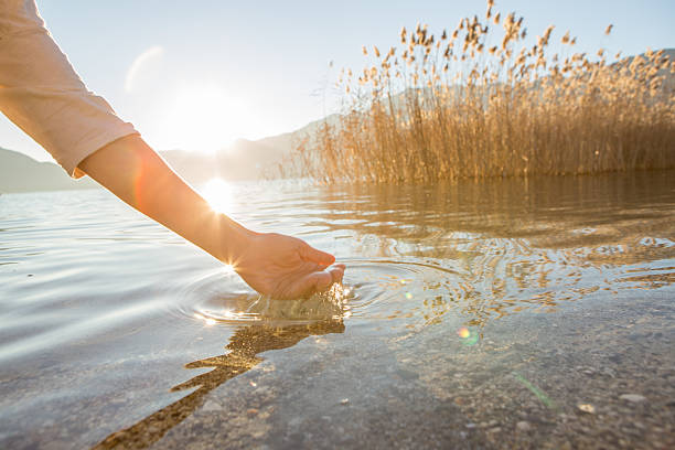 menschliche hand geschlossen, um frisches wasser von mountain lake - catch light stock-fotos und bilder