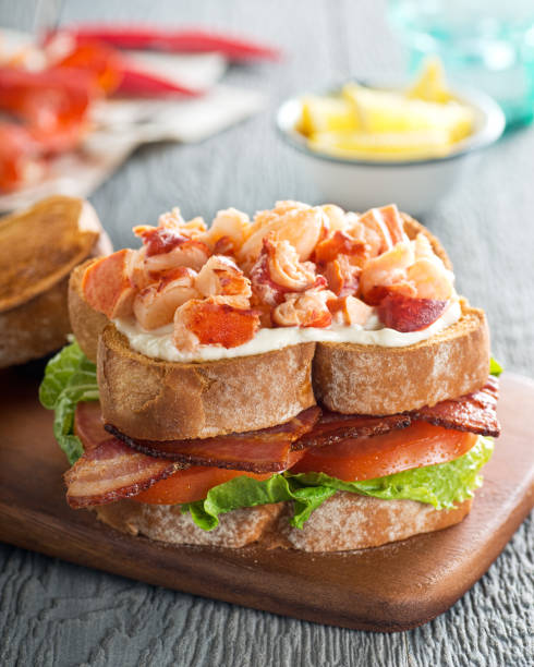 A delicious lobster club sandwich with bacon, lettuce, tomato, and mayonnaise on toasted bread.