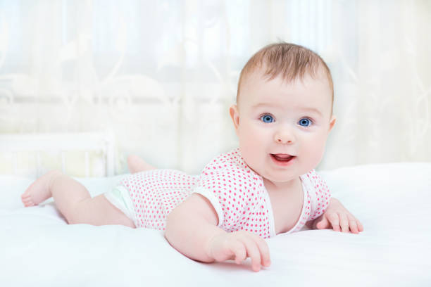 istock Cute baby smiling while lying on a white bed 639823898