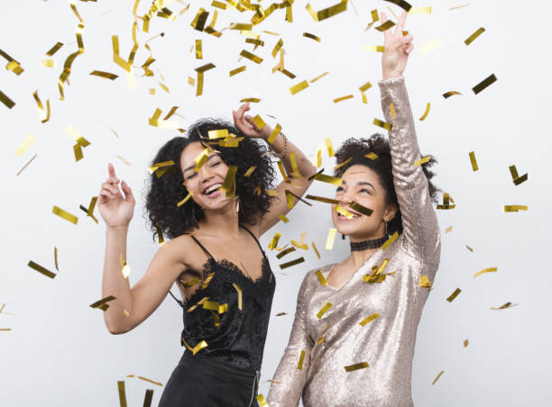 istock Young female friends having fun and dancing under confetti 639828674