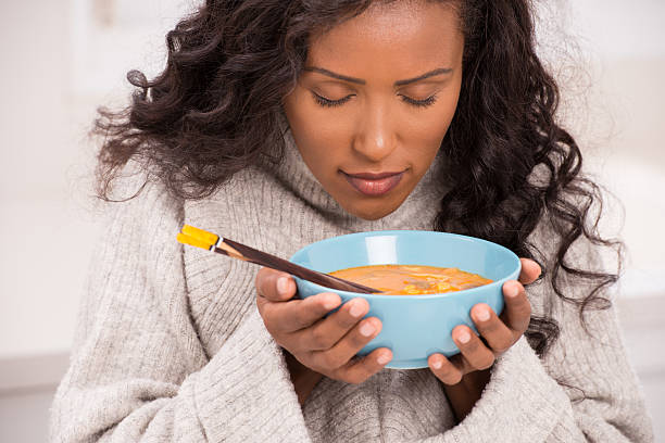 Woman enjoying soup. Beautiful young woman eating tom Yum soup, closing her eyes enjoying aroma of delicious soup. soup stock pictures, royalty-free photos & images