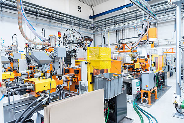 Injection moulding machines inside of plastic factory Horizontal color image of automated injection moulding machine sworking on plastic parts production. Powerful molding machinery in factory arranged in a row. metal crate stock pictures, royalty-free photos & images