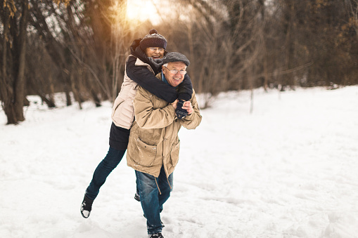 A photo of two elderly people having fun in the snow. They are retired and they enjoy the winter season.