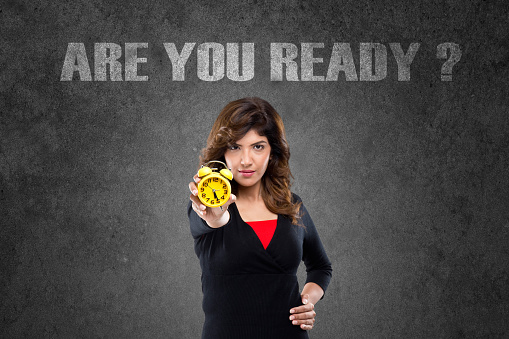 Portrait of young businesswoman showing yellow alarm clock, Are You Ready business concept