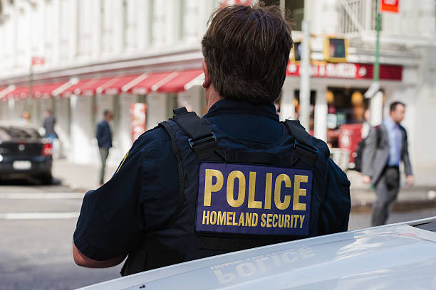 Pollce Homeland Security New York, USA - October 5, 2016: The back of a Homeland Security officers vest late in the day in Lower Manhattan as a man passes late in the day. department of homeland security stock pictures, royalty-free photos & images