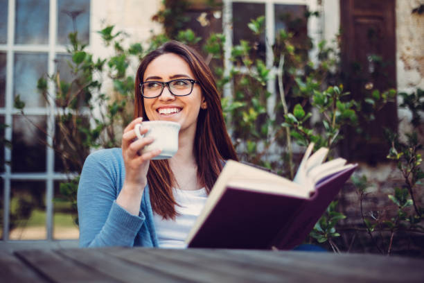 girl enjoying the weekend outside - woman with glasses reading a book imagens e fotografias de stock