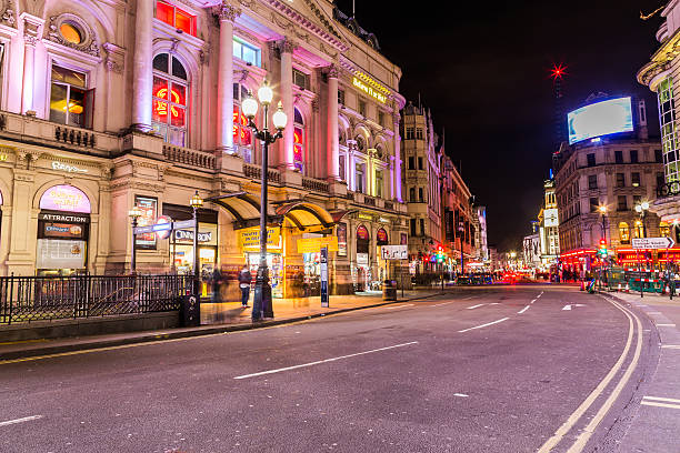 London, UK - November 1, 2013: Four young people are taking a break at the foot of the statue of Eros. Early 19th Century buildings line the square, housing theaters, restaurants, stores and entertainment.